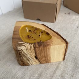 Handmade natural beeswax candle in rustic ash wood vessel with bark texture