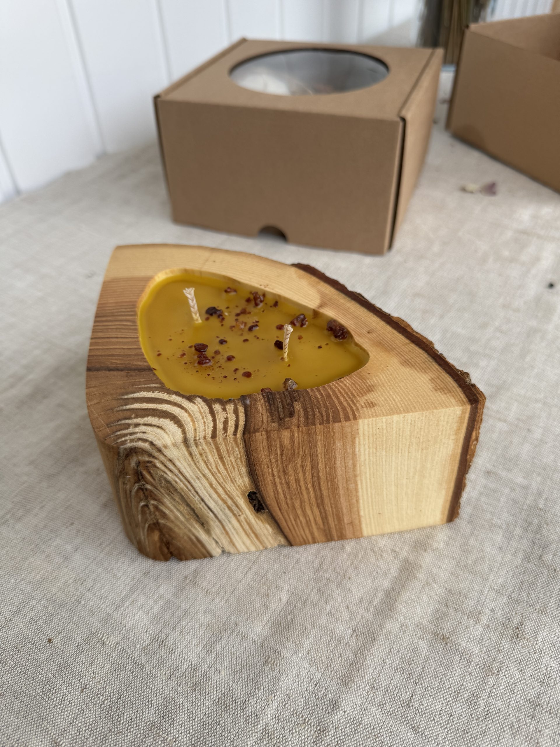 Handmade natural beeswax candle in rustic ash wood vessel with bark texture