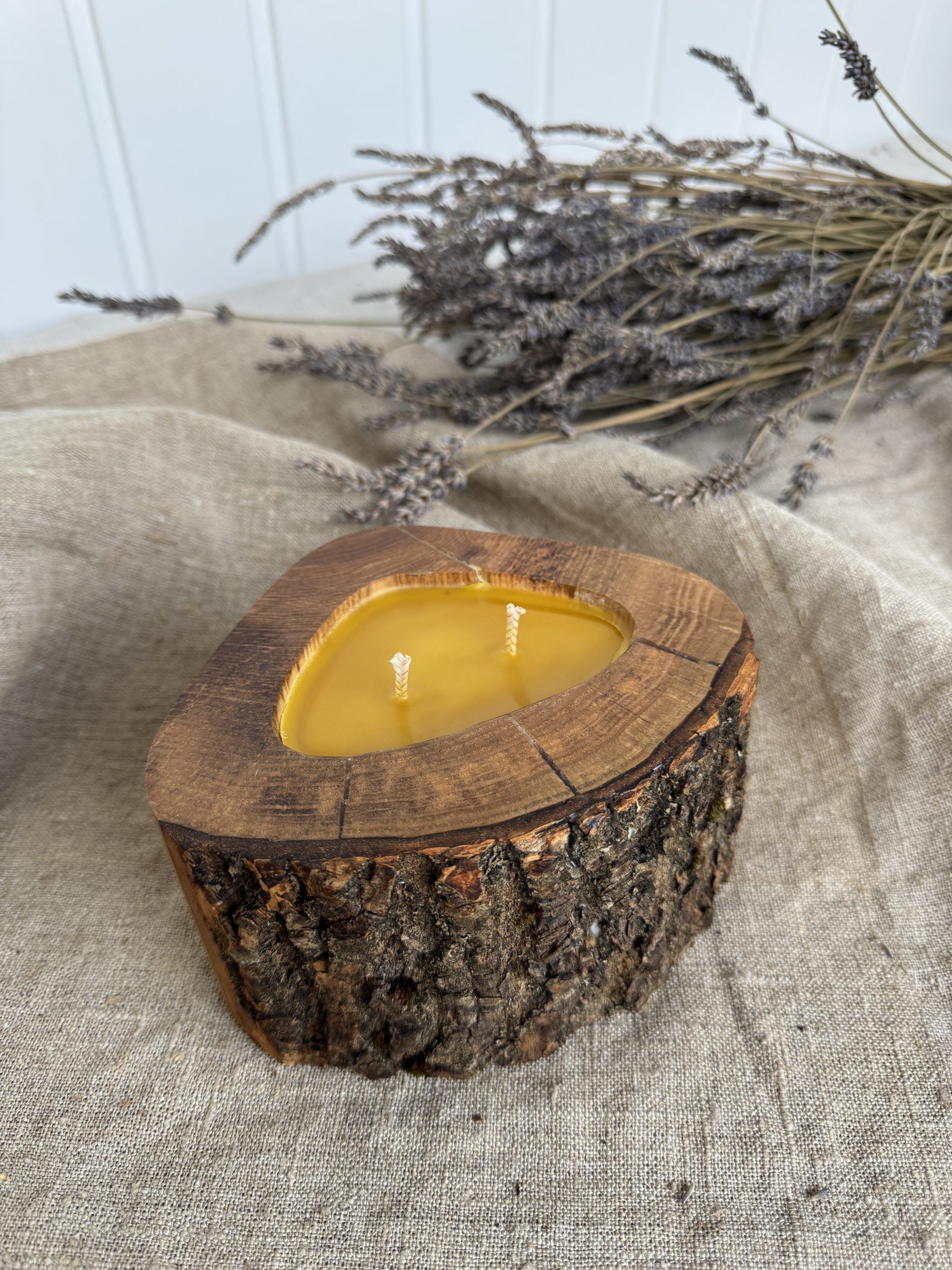 Handmade natural beeswax candle in rustic ash wood vessel with preserved bark texture