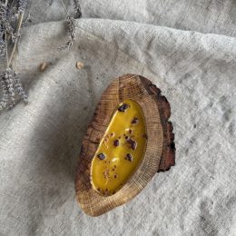 Handmade natural beeswax candle with propolis in rustic oak wood vessel with preserved bark texture