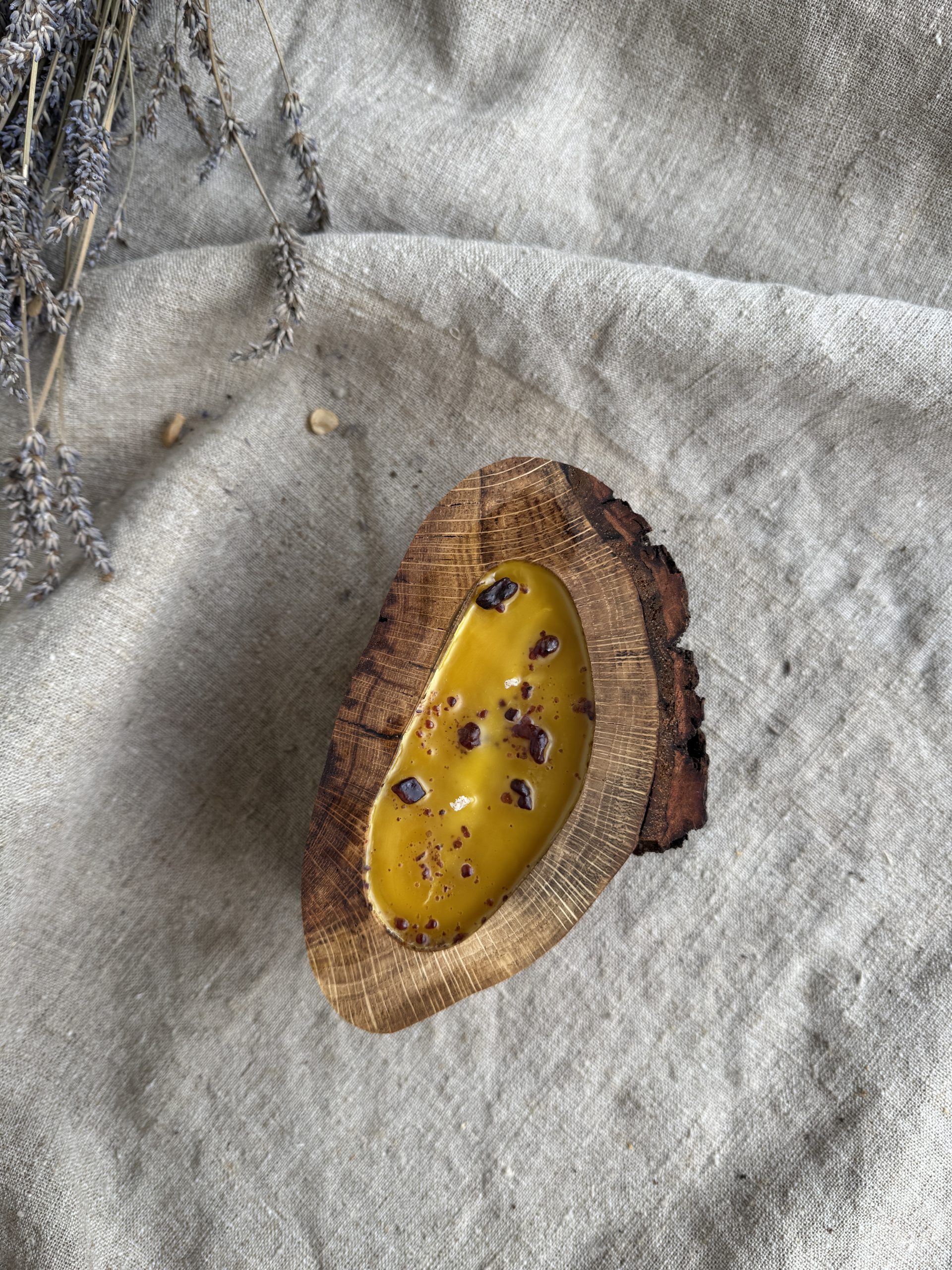 Handmade natural beeswax candle with propolis in rustic oak wood vessel with preserved bark texture