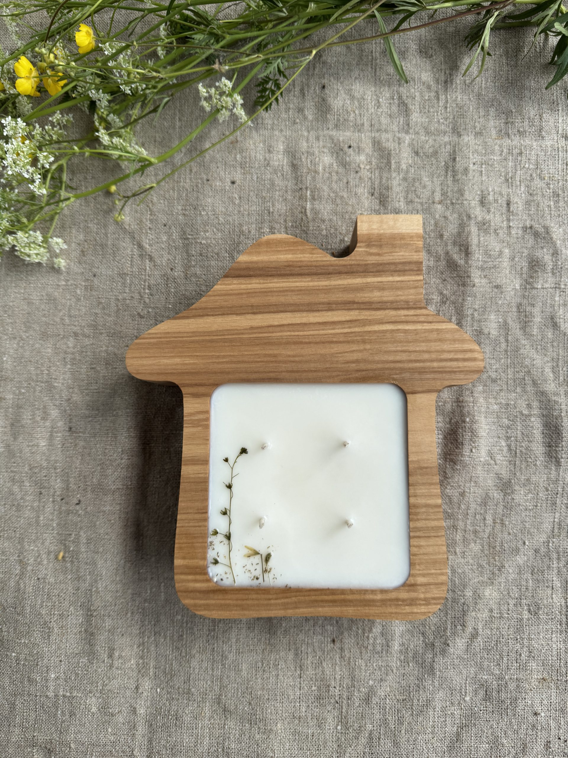 Handmade house-shaped ash wood soy candle with four cotton wicks and natural botanical decoration