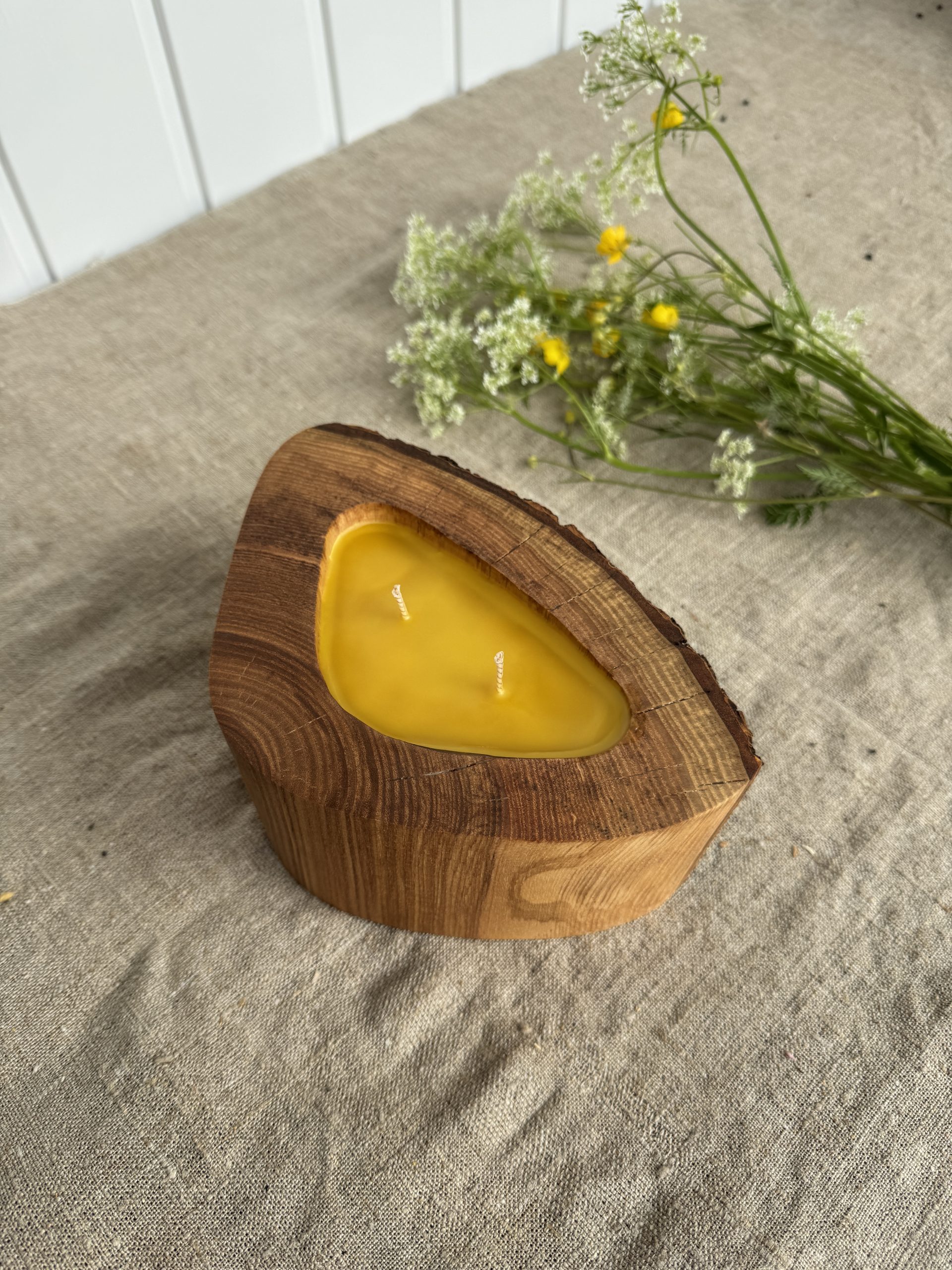 Handmade ash wood candle filled with natural beeswax in a unique triangular wooden vessel