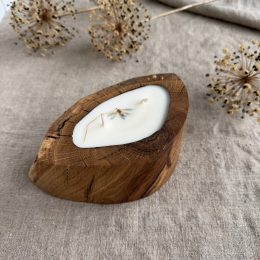 Handmade vanilla scented candle in a rustic oak wood vessel with natural wood grain and botanical decoration